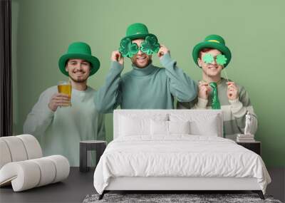 Happy young men in leprechaun's hats with beer, clovers and party glasses on green background. St. Patrick's Day celebration Wall mural