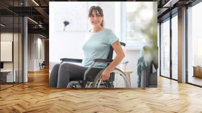 Happy young woman in wheelchair at home Wall mural