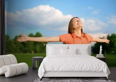 Happy young woman resting in park on sunny day Wall mural