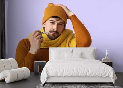 Ill young man with thermometer on lilac background Wall mural