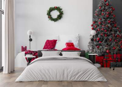 Interior of festive bedroom with comfortable bed, wreath and Christmas tree Wall mural