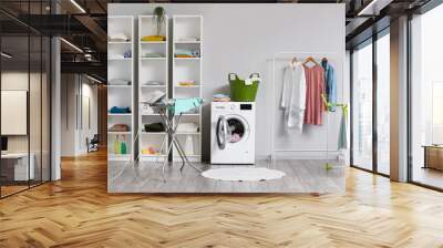 Interior of light laundry room with shelf units, washing machine and rack with clothes Wall mural