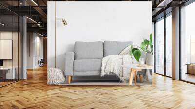 Interior of light living room with cozy grey sofa, houseplant on coffee table and pouf Wall mural