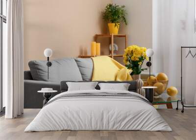 Interior of modern living room with grey sofa, vase with yellow flowers and oranges on coffee table, closeup Wall mural