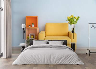 interior of modern room with comfortable armchair, shelf unit and spring flowers near light wall Wall mural