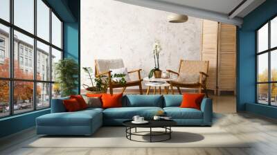 Interior of room with armchairs and table near light wall Wall mural