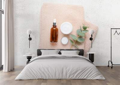 Jars with natural cosmetic cream, bottle of essential oil and towel on light background Wall mural