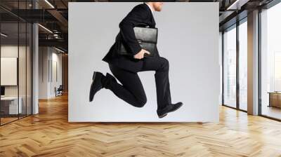 Jumping businessman with stylish briefcase on light background Wall mural