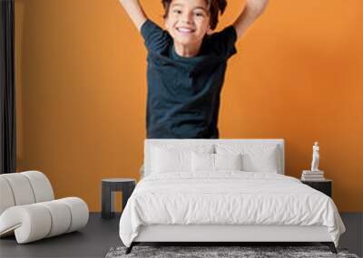 Jumping little boy on color background Wall mural