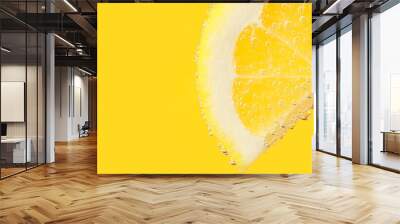 Lemon slice in water against yellow background with space for text, closeup Wall mural