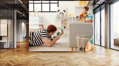 Little boy and his father playing with toy guns at home Wall mural