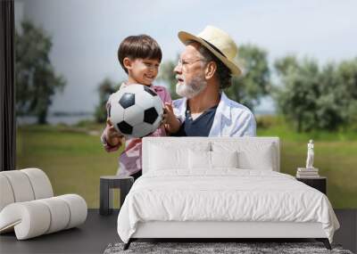 Little boy with ball and his grandfather outdoors Wall mural