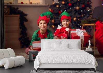 Little children in costume of elf and with gifts in room decorated for Christmas Wall mural