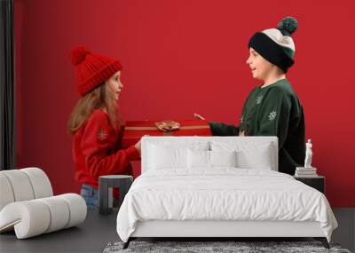 Little children with Christmas gift on red background Wall mural