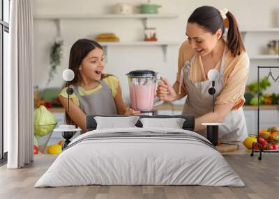 Little girl and her mother making smoothie with blender in kitchen Wall mural