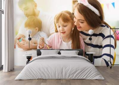 Little girl and her mother painting Easter eggs at home Wall mural