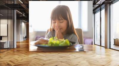 Little girl praying before meal at home Wall mural