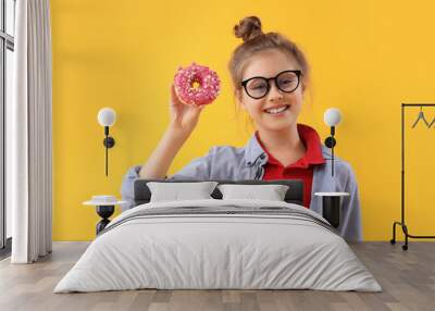 Little girl with tasty doughnut on yellow background Wall mural