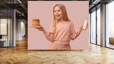 Little girl with tasty pancakes and bottle of milk on beige background Wall mural