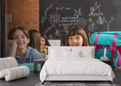 Little pupils with backpack and lunchbox sitting in classroom Wall mural