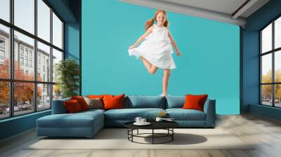 Little redhead girl in white dress jumping on blue background Wall mural