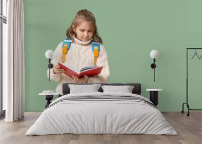 Little schoolgirl reading book on green background Wall mural