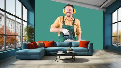 Male carpenter sawing wooden plank with jigsaw on green background Wall mural