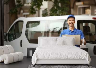 Male courier with parcel near automobile outdoors Wall mural