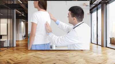 Male doctor checking posture of young woman in clinic Wall mural