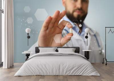 Male doctor holding pill on grey background, closeup Wall mural