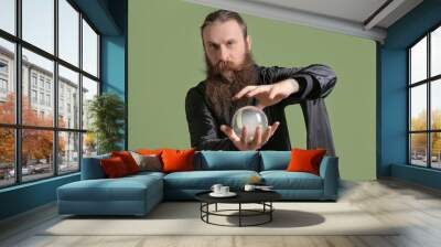 Male fortune teller with crystal ball on color background Wall mural