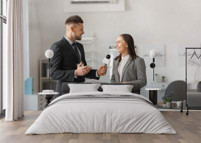 Male journalist having interview with woman indoors Wall mural