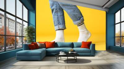 Male legs in socks and jeans on color background Wall mural