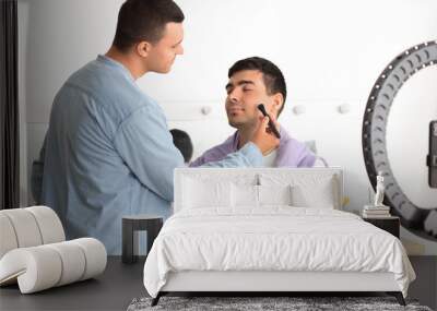 Male makeup artist working with client in dressing room Wall mural