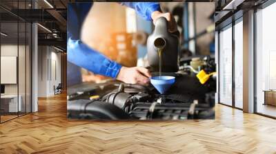 Male mechanic refilling car oil in service center Wall mural