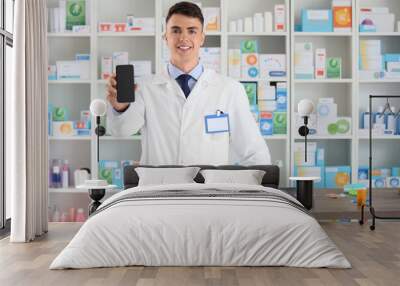 Male pharmacist with mobile phone at pharmacy Wall mural