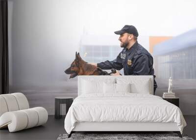 Male police officer with dog patrolling city street Wall mural