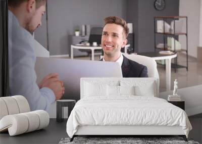 Male receptionist working with visitor in office Wall mural