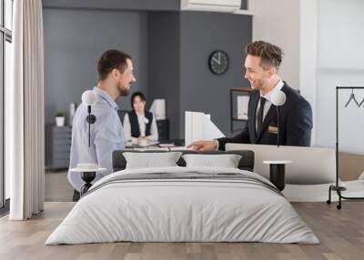 Male receptionist working with visitor in office Wall mural