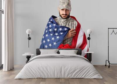 Male soldier with USA flag and flowers praying on light background. Veterans Day celebration Wall mural