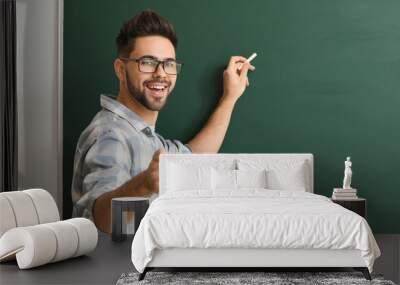 Male teacher writing on blackboard in classroom Wall mural