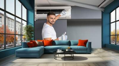 Male technician repairing air conditioner indoors Wall mural