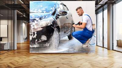 Male worker washing car outdoors Wall mural