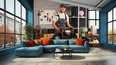 Male worker with bag of tools repairing coffee machine in workshop Wall mural