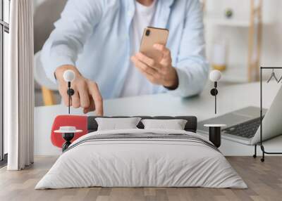 Man connecting mobile phone to wireless portable speaker on table, closeup Wall mural