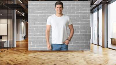 Man in stylish t-shirt on brick background Wall mural