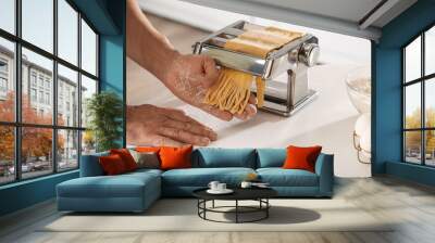 Man making pasta with machine at table in kitchen, closeup Wall mural