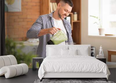 Man with healthy homemade smoothie in kitchen Wall mural