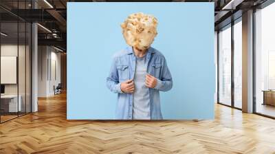 Man with tasty popcorn ball instead of his head on light blue background Wall mural