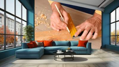 Mature carpenter measuring wooden board at table in workshop, closeup Wall mural